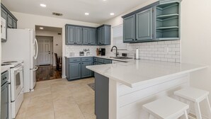 A modern kitchen with white countertops, blue cabinets, and a large island. - 3 King Bedrooms • Hot Tub • Game Room • Near Six Flags & SeaWorld (San Antonio)
