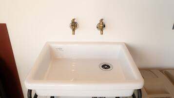 A white rectangular sink with two brass faucets, a drain, and a visible pipe beneath.