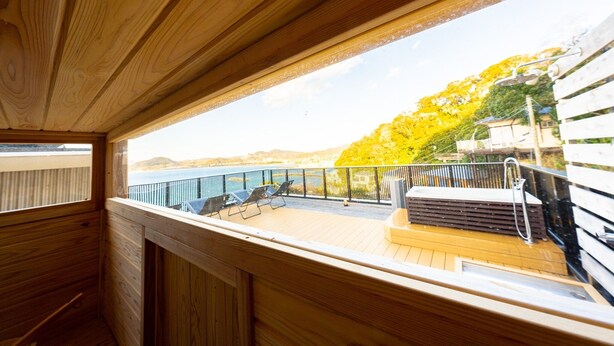 A wooden deck with a view of a body of water and trees. - The View minamiboso (Minamiboso)