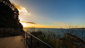 A wooden deck with a railing overlooking a body of water and a distant shoreline. - The View minamiboso (Minamiboso)