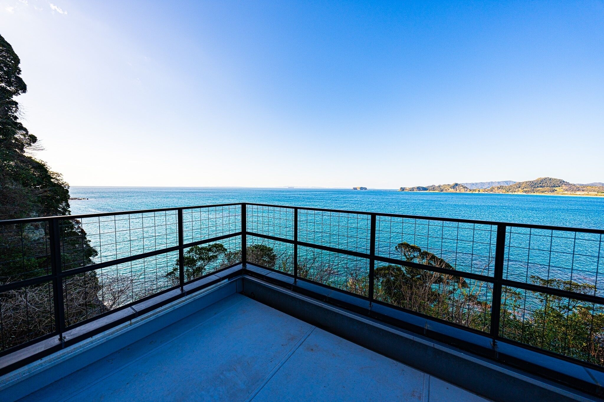 Een balkon met vrij uitzicht op zee en het verre land.