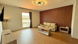 A modern living room with a sofa, coffee table, and a TV on a stand. - Chara Hotel (Bandung)