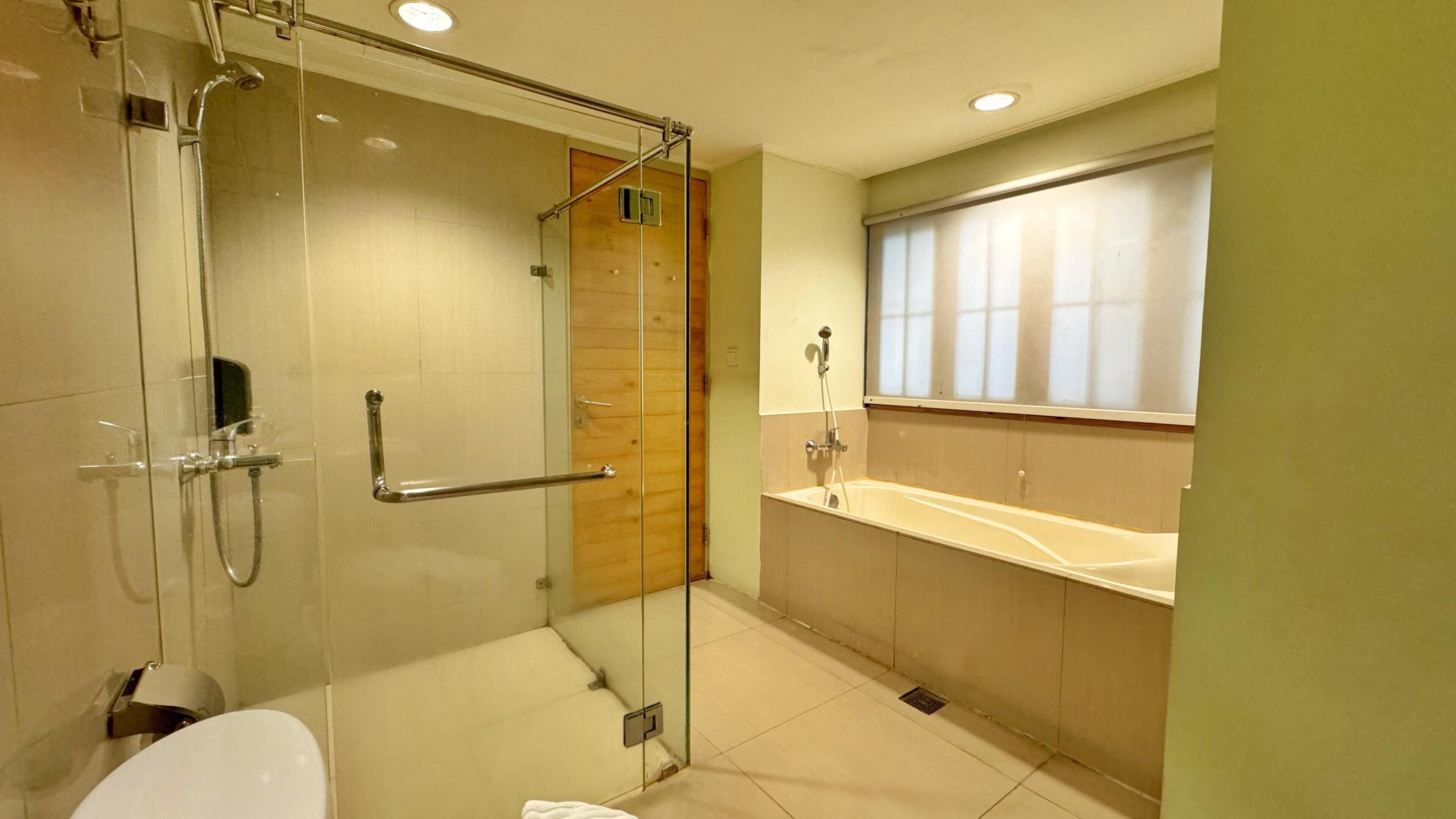 A modern bathroom with a glass-enclosed shower, a white sink, and a wooden vanity.