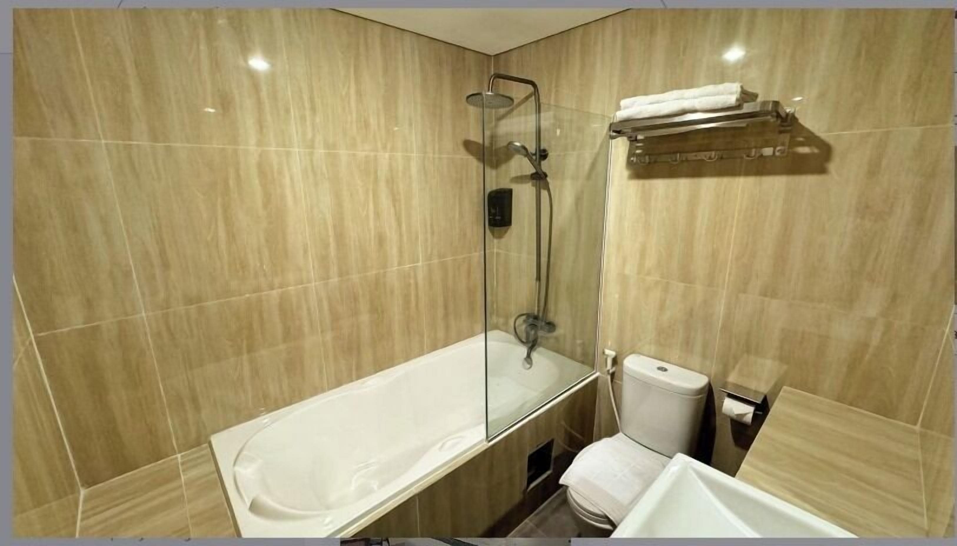 A modern bathroom with a glass-enclosed shower, a white bathtub, and a toilet.