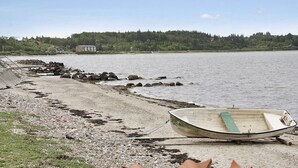 A beach with a row of rocks and a small boat tied to the shore. - "Pauliina" - 10m to the fjord by Interhome (Roslev)