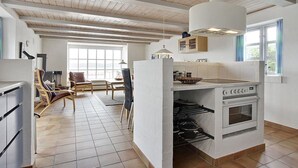 A modern kitchen with a central island, wooden ceiling beams, and a dining area with chairs and a table. - "Pauliina" - 10m to the fjord by Interhome (Roslev)