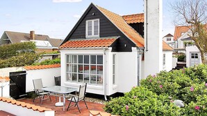 A house with a black roof, white walls, and a small patio with a table and chairs. - "Pauliina" - 10m to the fjord by Interhome (Roslev)