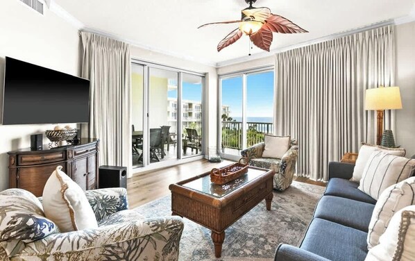A spacious living room with a large flat-screen TV, a wooden coffee table, and a sofa.