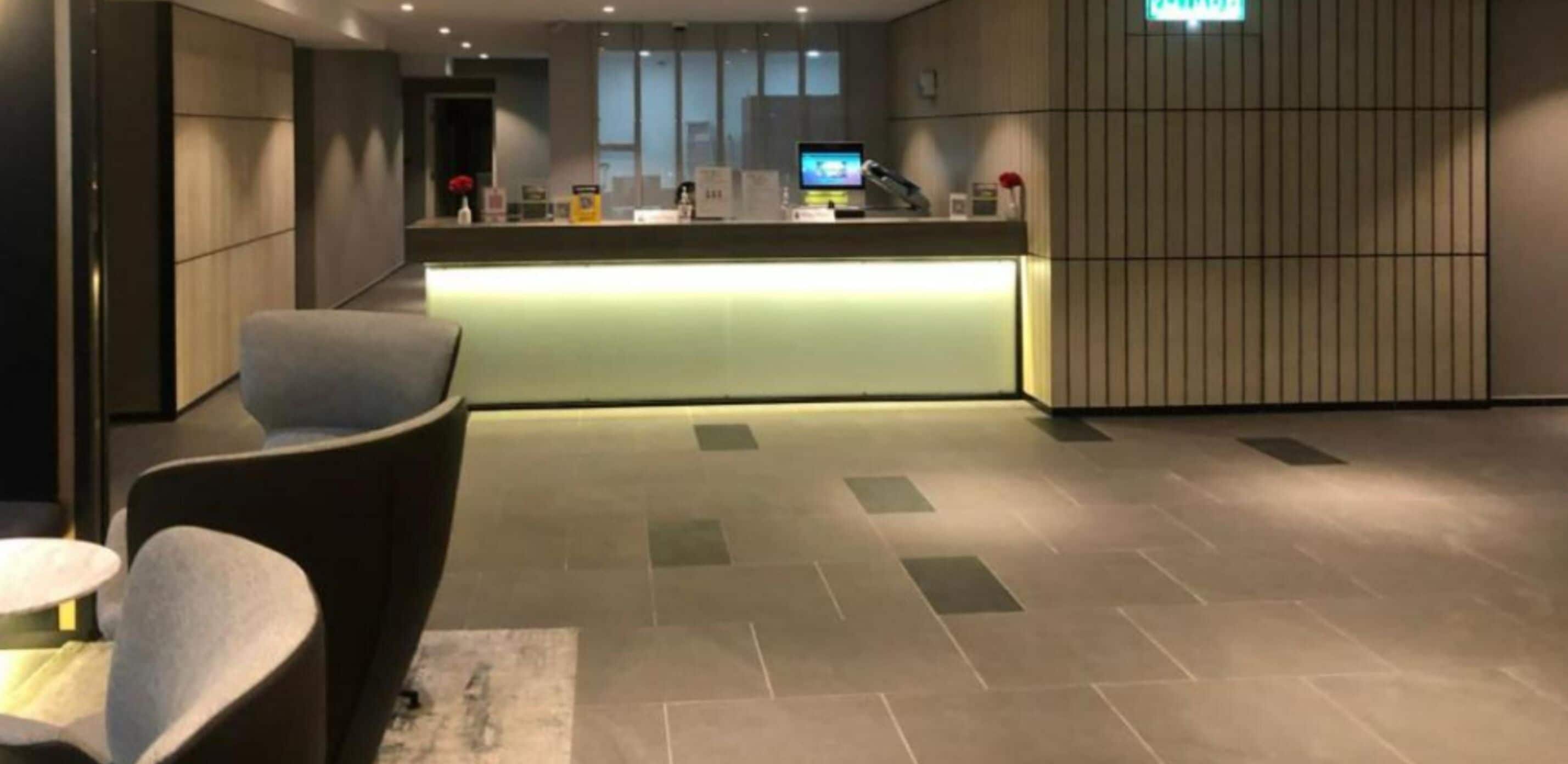 Un área de recepción moderna con mostrador, asientos y suelo de baldosas.