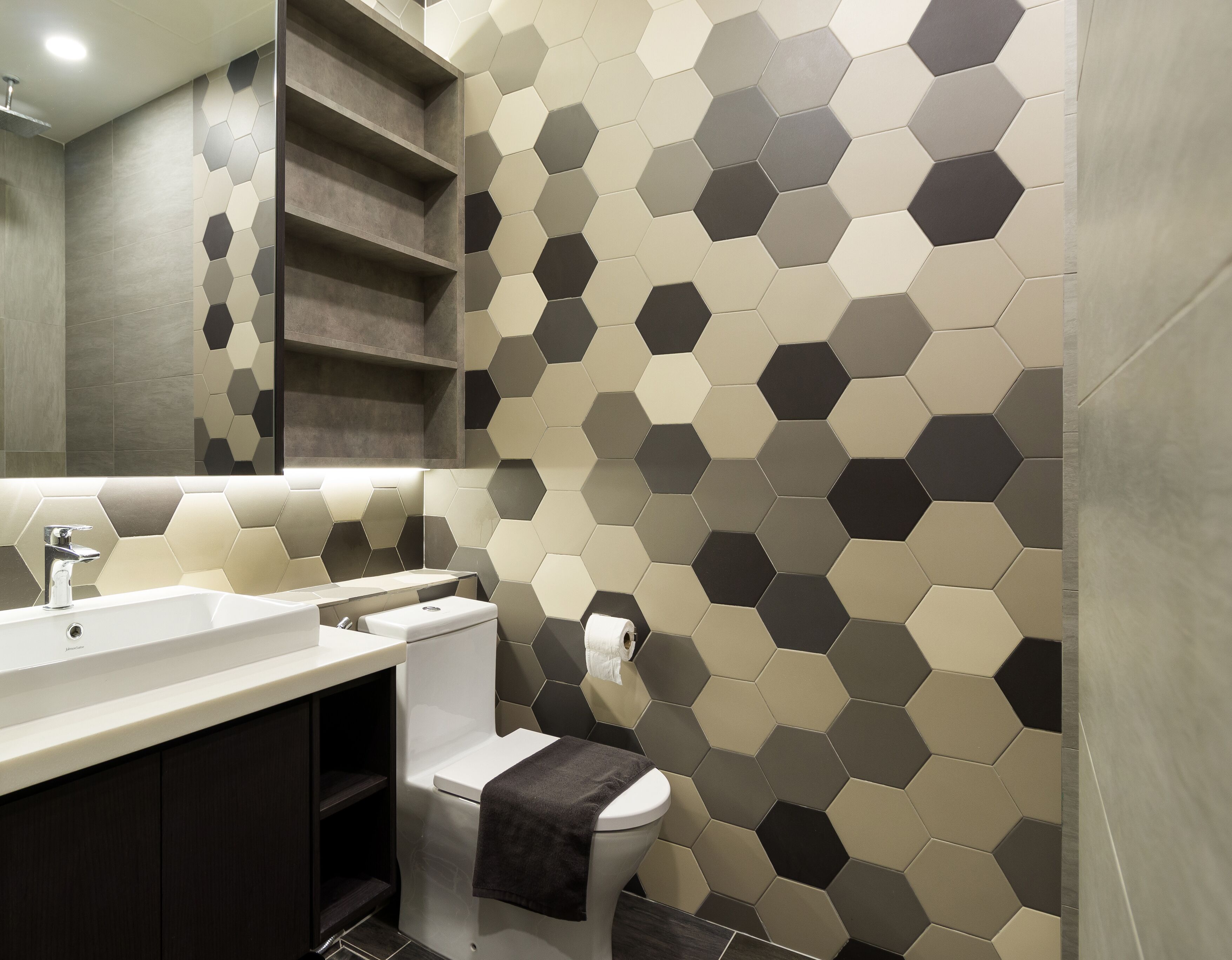 A modern bathroom with a hexagonal tile wall, a white sink, and a toilet.