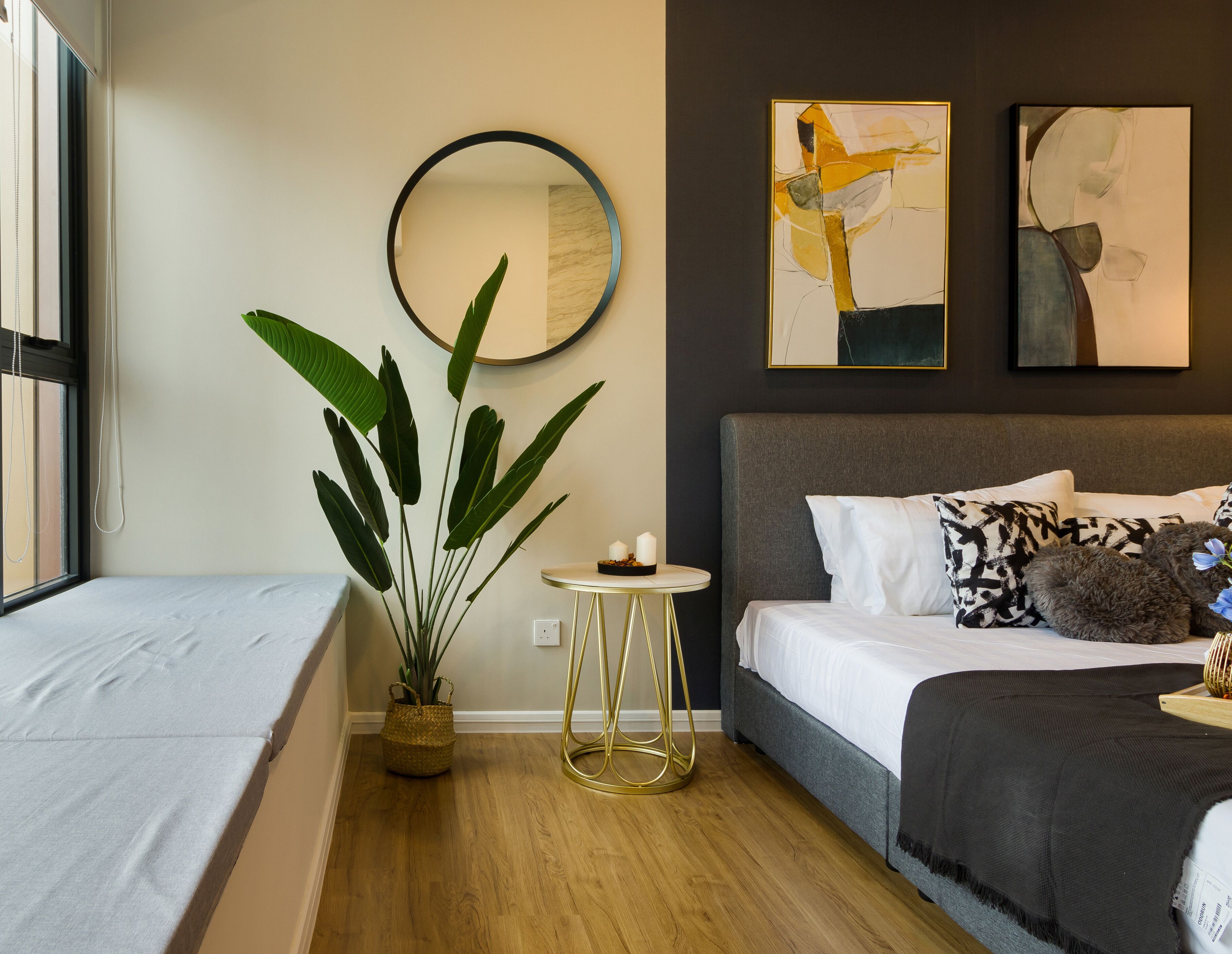 Un dormitorio moderno con una cama, una mesita de noche, una planta en maceta y arte abstracto en la pared.