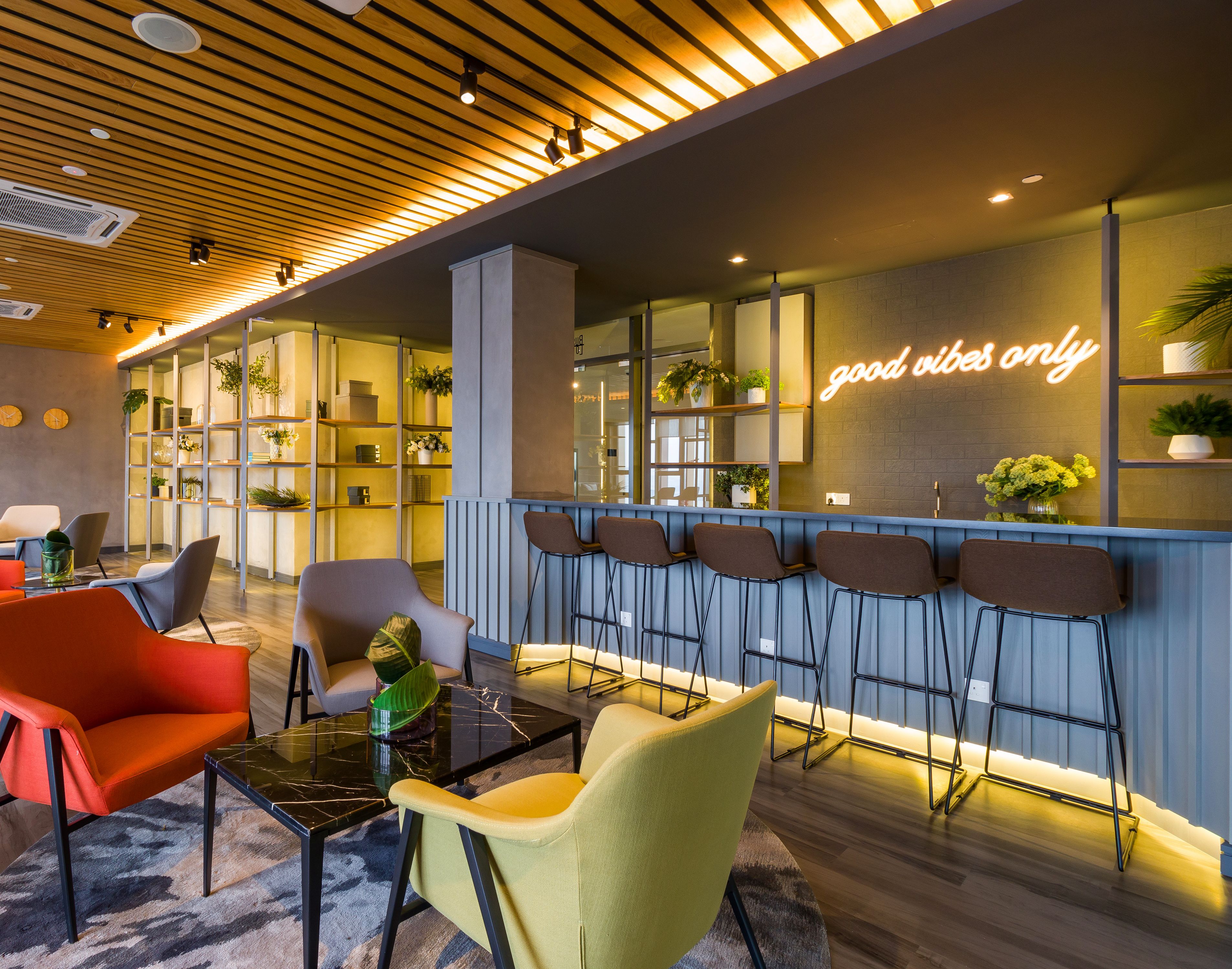 Uma área de estar moderna com assentos, um bar e um letreiro de neon.