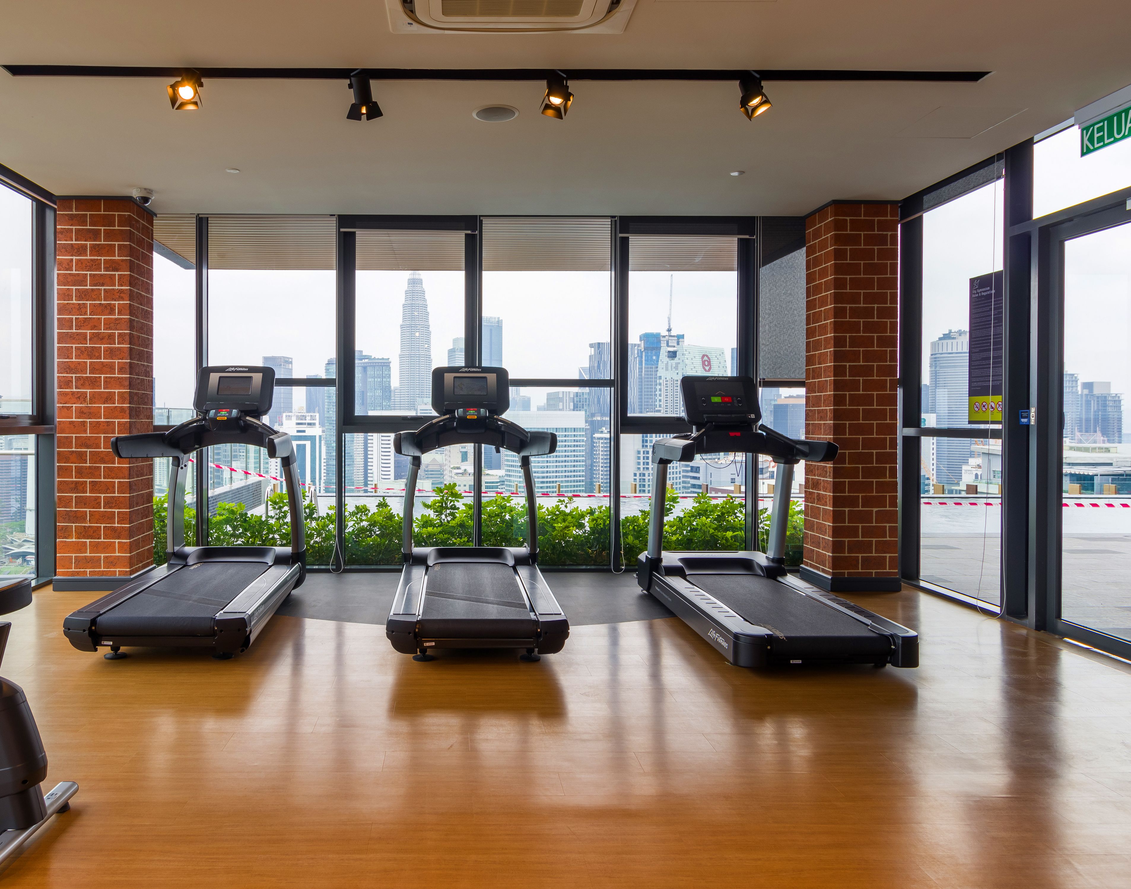 A gym with treadmills, an elliptical, and a stationary bike. It has large windows with a city view.