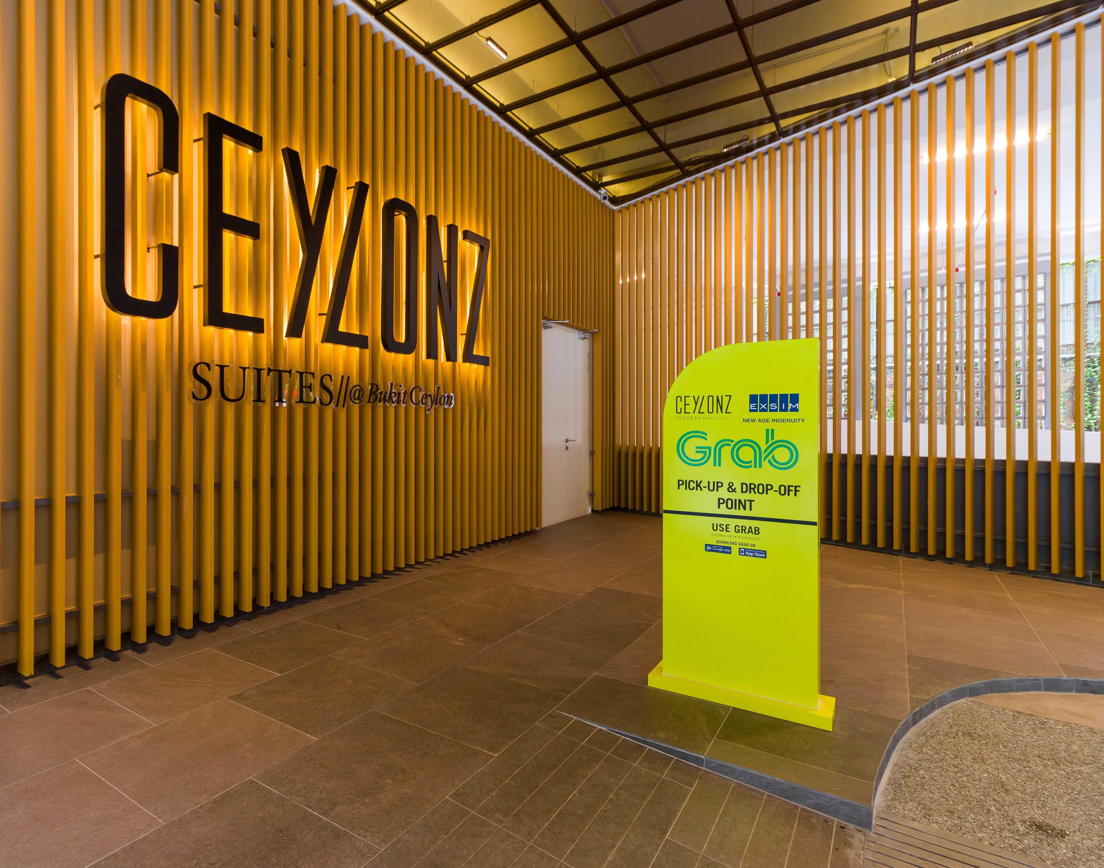A hotel lobby with a vertical wooden panel design and a bright yellow 'CEYLONZ' sign.