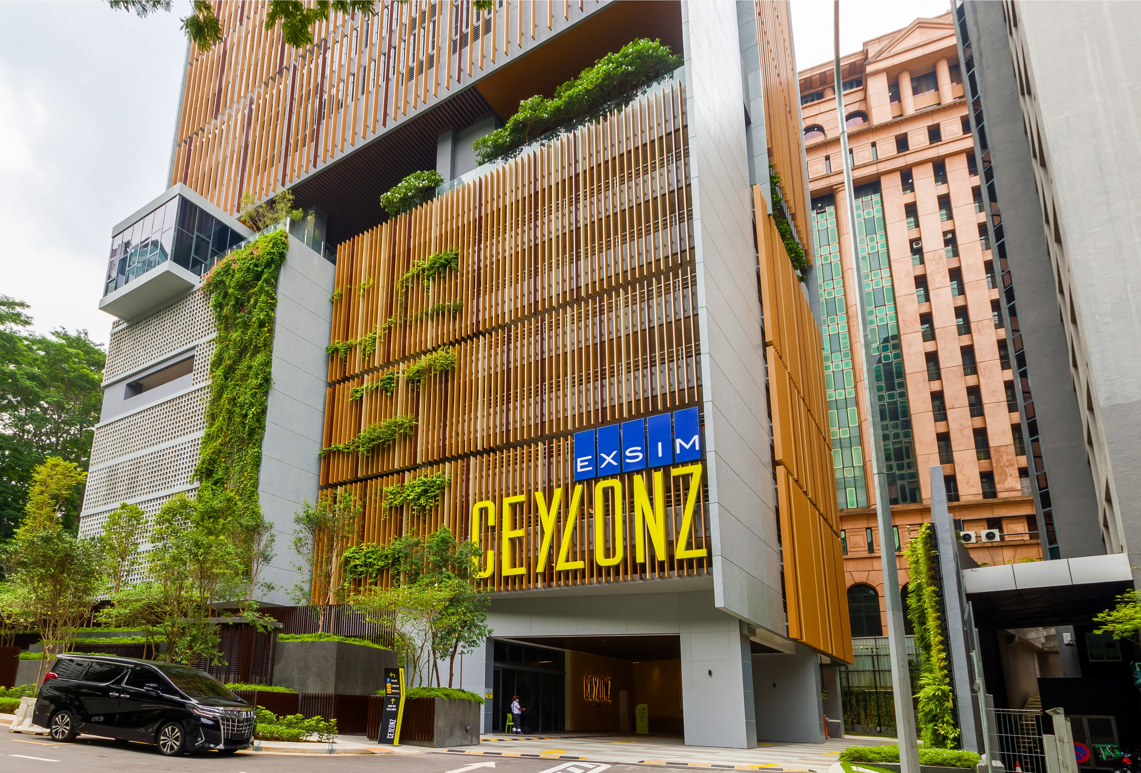 Un bâtiment moderne, orné d’une grande enseigne « CEYLON », avec des lambris en bois verticaux et de la verdure.