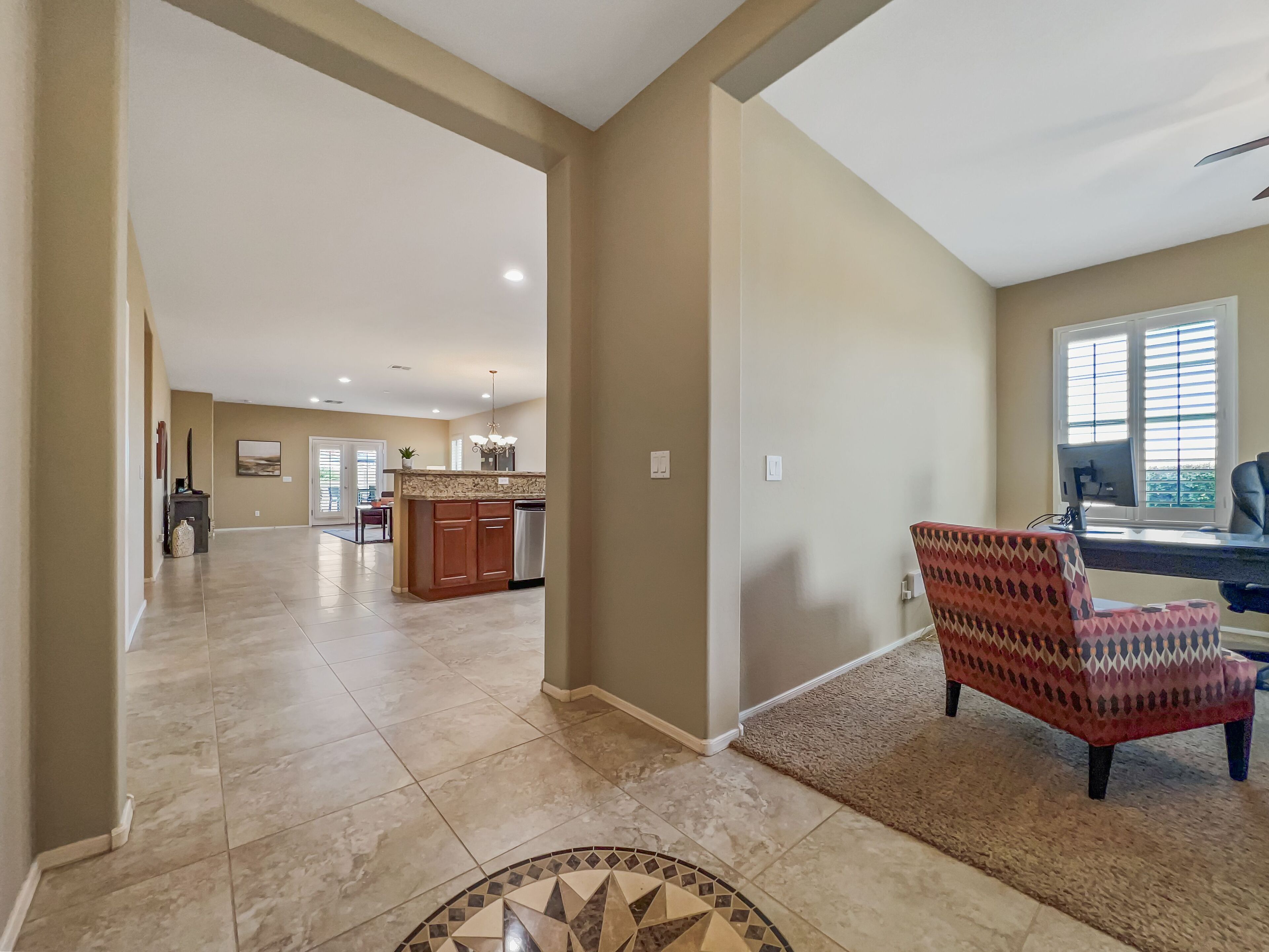 A spacious living area with a kitchen in the background, a dining area, and a large window providing natural light.