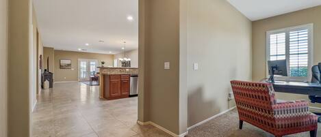 A spacious living area with a kitchen in the background, a dining area, and a large window providing natural light.