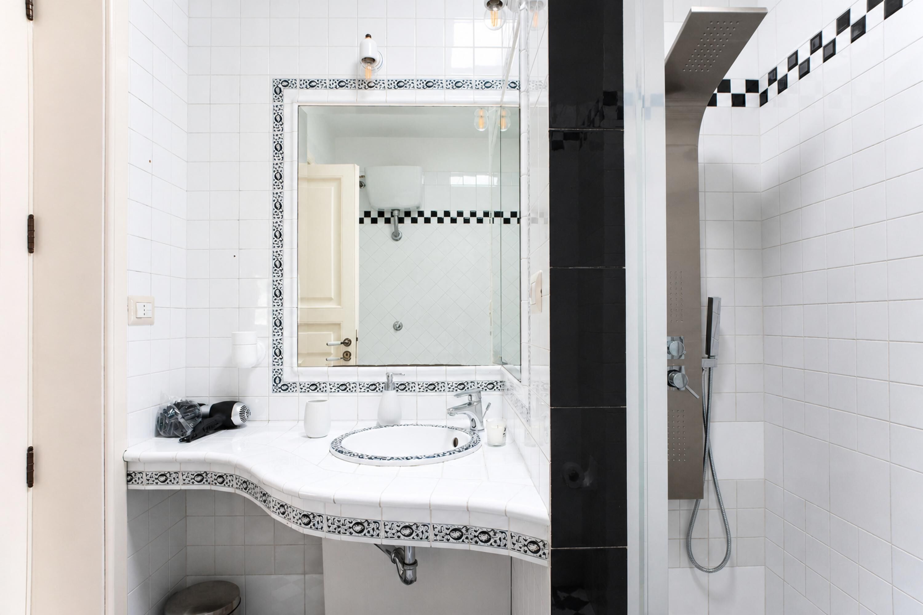 A bathroom with a white sink, a mirror, and a shower area.