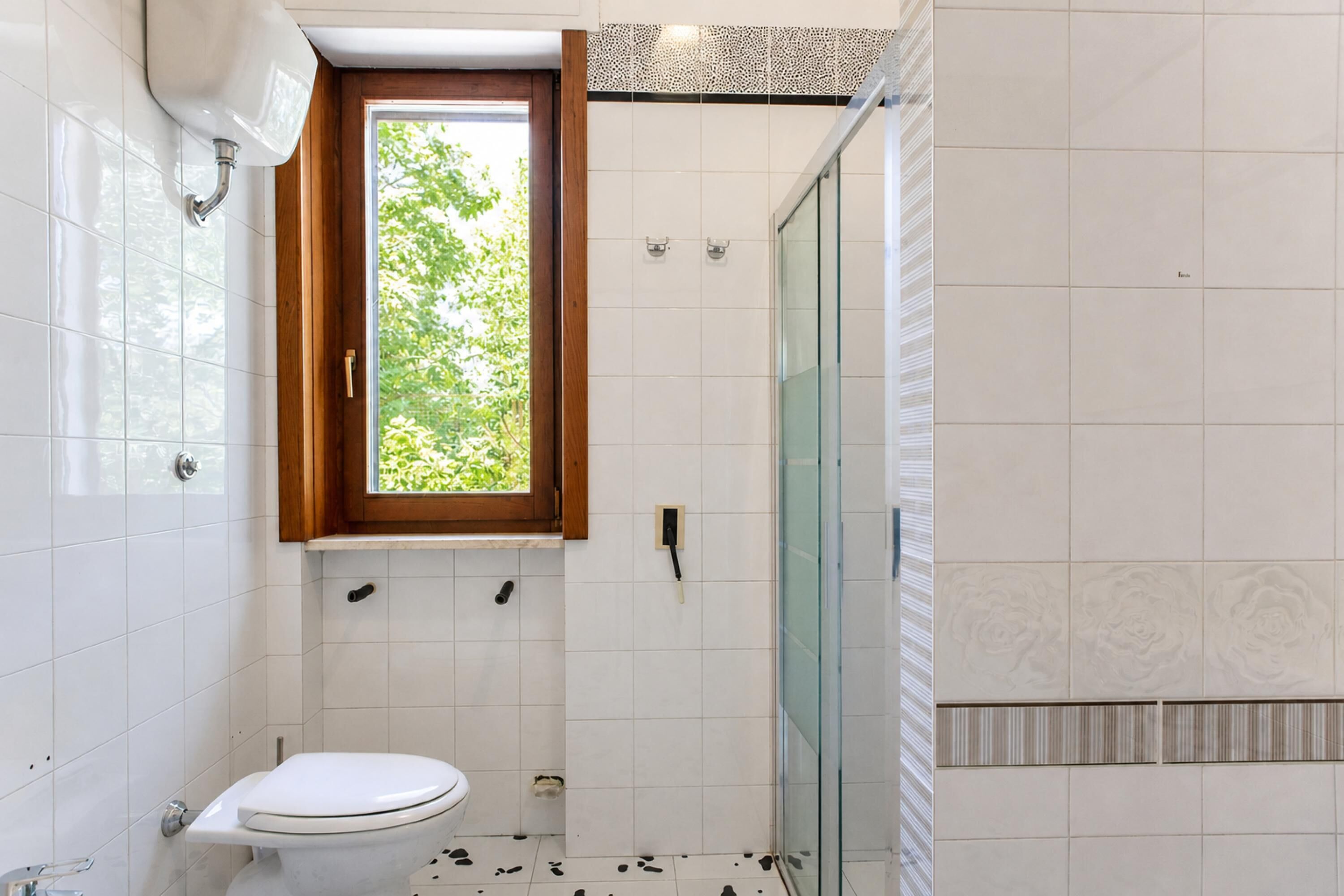 A bathroom with a toilet, a shower, and a window.
