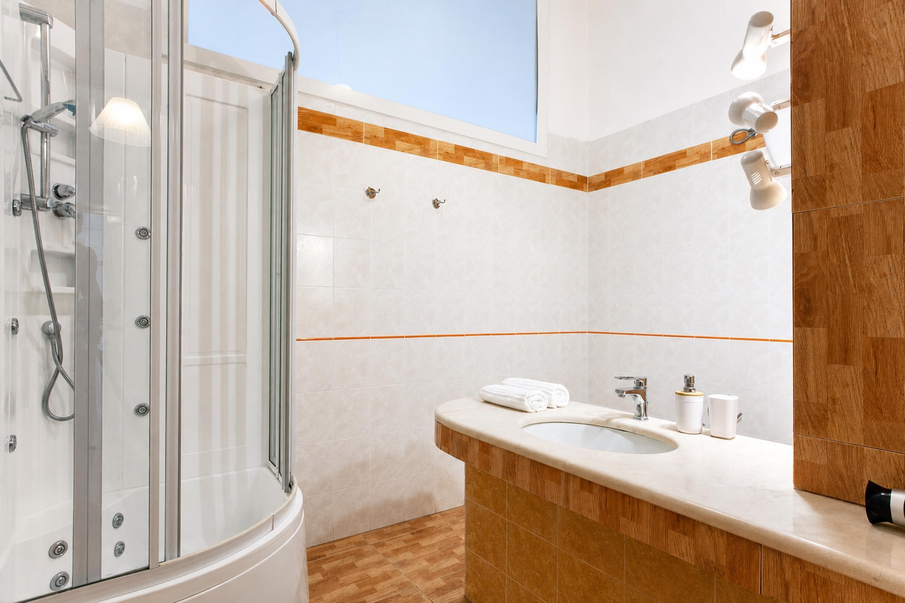 Un baño moderno con cabina de ducha de vidrio, un lavabo con espejo y una pared de acento de madera.