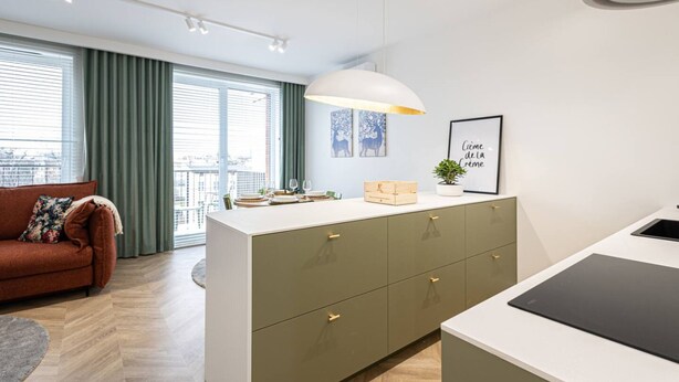 A modern living room with a sofa, a dining area with a table and chairs, and a kitchen with a countertop and cabinets. - Menta Panorama Apartment Widok na Oper Nova Brd (Bydgoszcz)