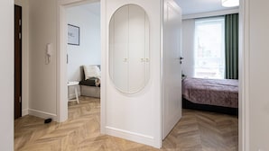 A hotel room with a bed, a small seating area, a white wardrobe, and a door leading to another room. - Menta Panorama Apartment Widok na Oper Nova Brd (Bydgoszcz)