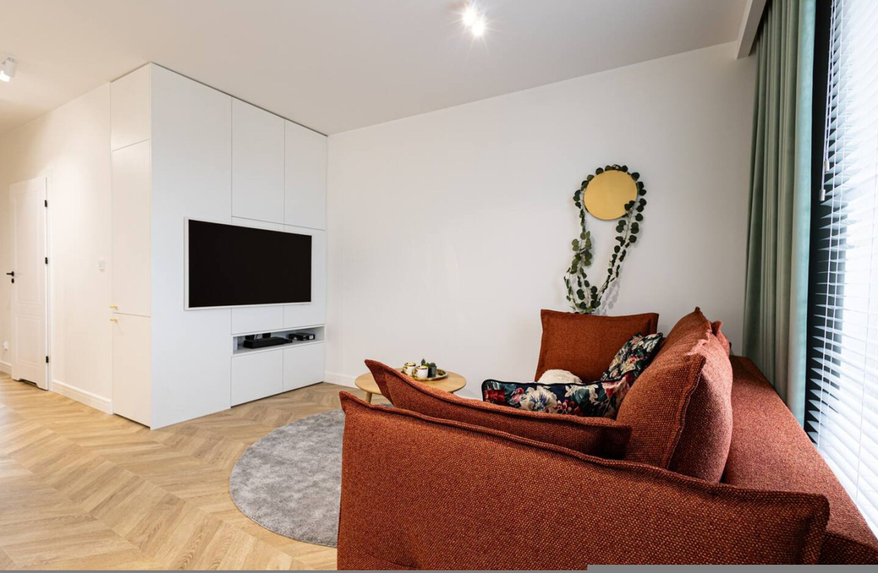 Una sala de estar moderna con un televisor de pantalla plana, un sofá y un elemento decorativo en la pared.