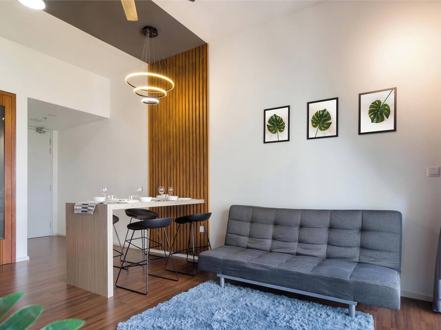 Uma sala de estar moderna com um sofá cinzento, uma mesa de jantar de madeira com cadeiras e três quadros de plantas na parede.