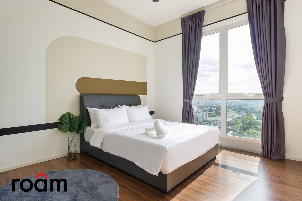 Ein modernes Schlafzimmer mit einem großen Bett, Blick auf die Stadt und einer Pflanze.