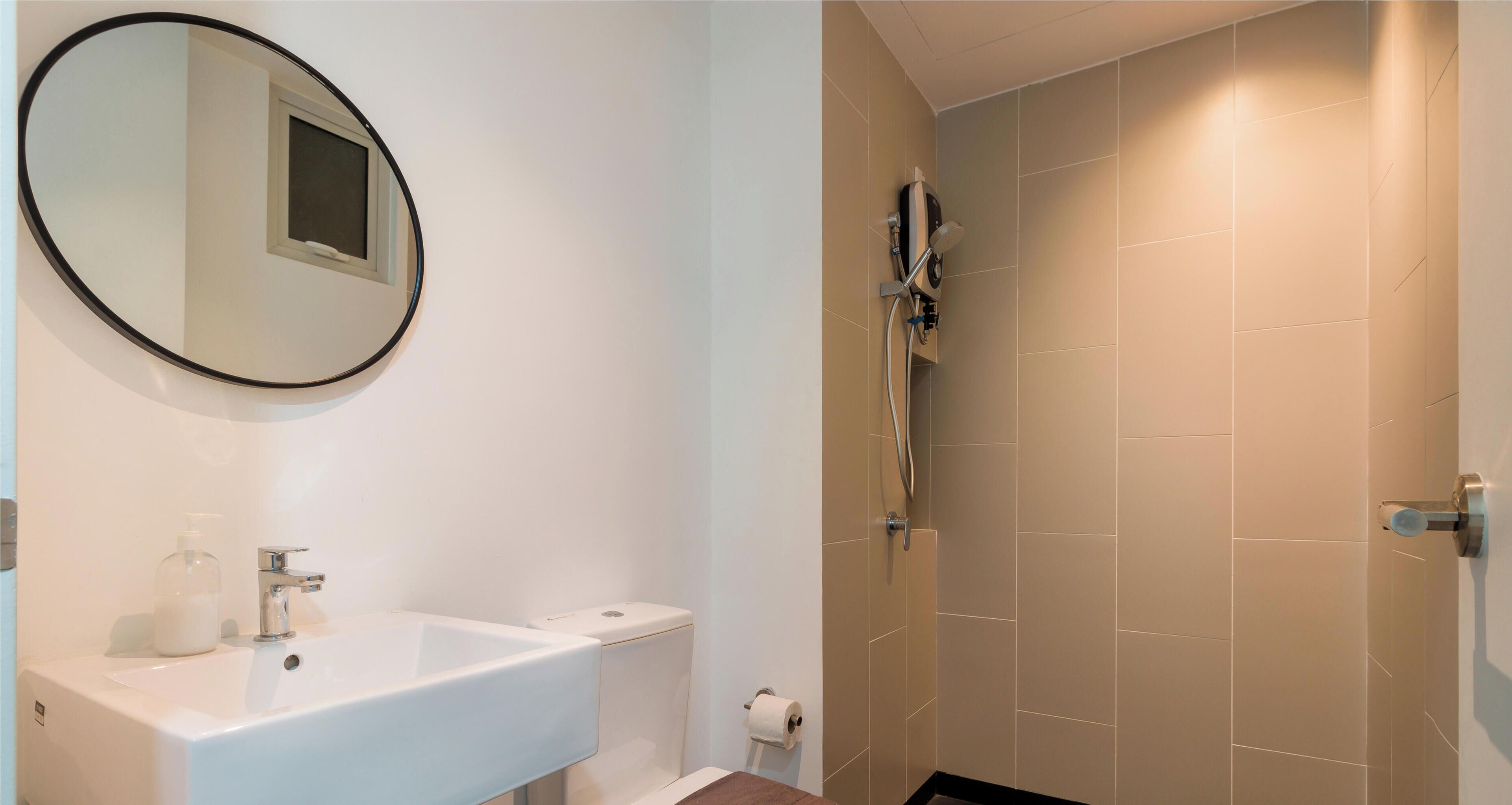 A bathroom with a white sink, a mirror, a toilet, and a shower area.