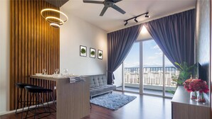 Un salon moderne comprenant un canapé, une table à manger et des chaises, un balcon avec vue et un ventilateur de plafond.