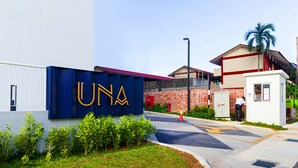 Un bâtiment sur lequel on peut lire l’inscription « UNA », et une petite construction à proximité, où se tient une personne.