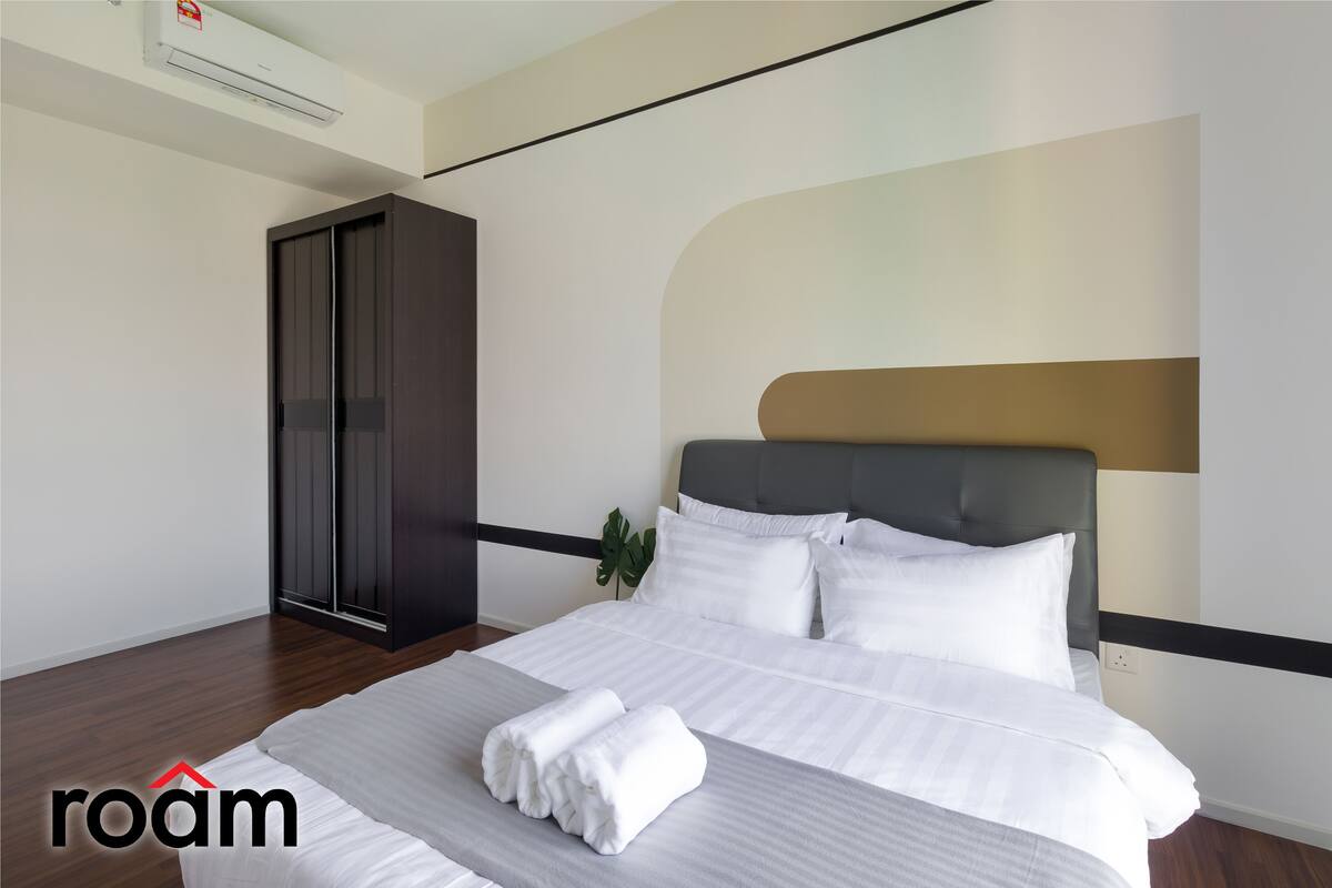 Ein modernes Hotelzimmer mit einem ordentlich bezogenen Bett, einem dunklen Wandschrank und einem großen Fenster.