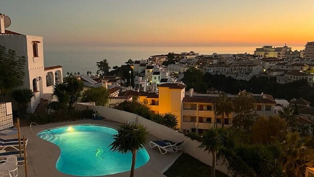 A swimming pool with lounge chairs, surrounded by greenery and overlooking a coastal town at sunset. - AP393 LOS ALMENDROS (Nerja)