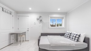 A bedroom with a bed, a desk, and a window.