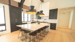 A modern kitchen with a large island, bar stools, pendant lighting, and dark cabinetry. - Wolf Rock Home 82 (Keystone)