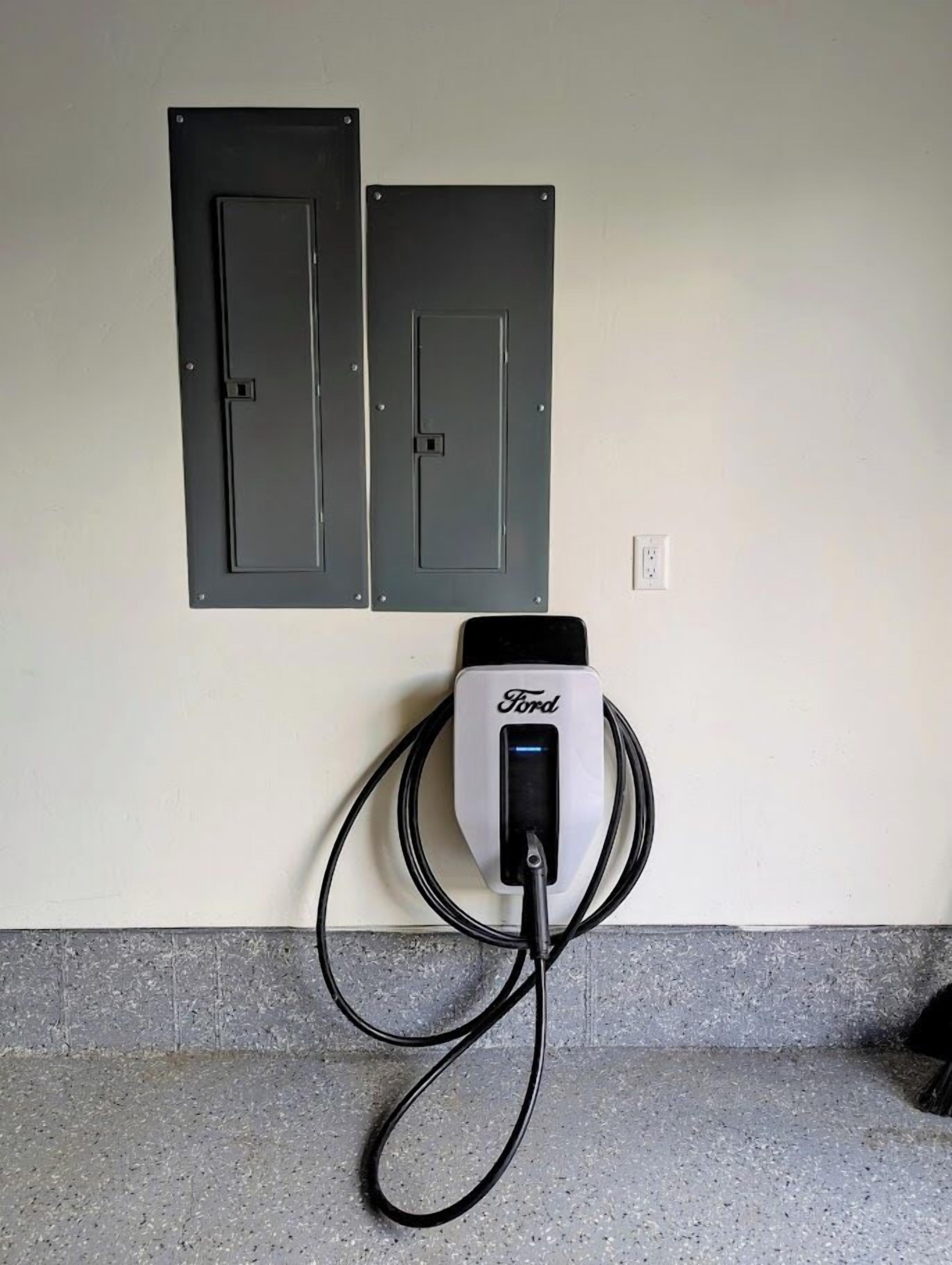 A wall-mounted electric vehicle charging station with a cable connected to it.