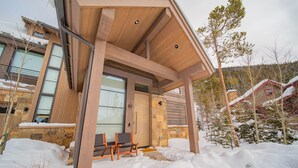 A modern house with a stone facade, large windows, and a wooden porch. - Wolf Rock Home 82 (Keystone)