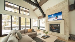 A modern living room with a large sectional sofa, a fireplace, and large windows offering a view of the outdoors. - Wolf Rock Home 82 (Keystone)