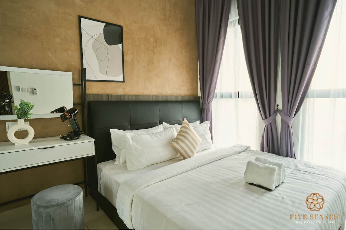 Une chambre d’hôtel avec un lit, un bureau, une chaise, un miroir et une fenêtre avec des rideaux.
