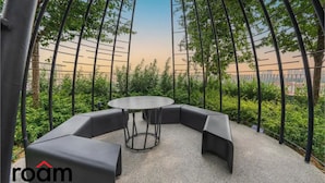 A circular seating area with a central table, surrounded by black cushioned benches, set on a gravel surface. - Trion Kuala Lumpur by Roam (Kuala Lumpur)