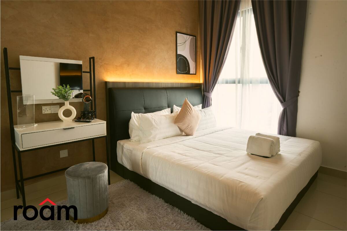 Une chambre d’hôtel moderne, équipée d’un lit, d’une table de chevet et d’une grande fenêtre avec des rideaux.