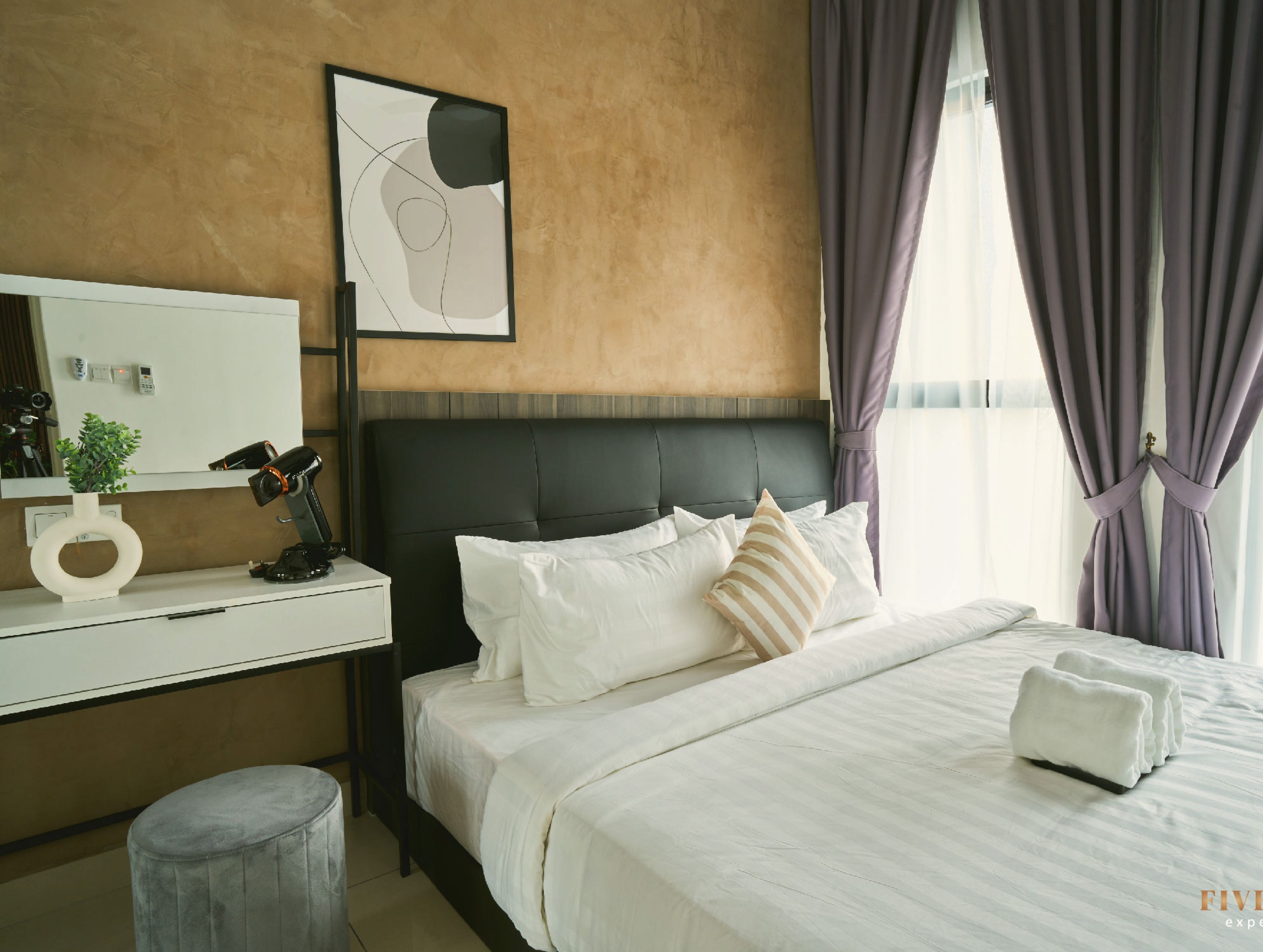 Une chambre d’hôtel avec un lit, un bureau, une chaise, un miroir et une fenêtre avec des rideaux.