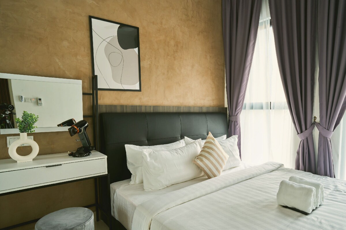 Ein Hotelzimmer mit Bett, Schreibtisch, Stuhl, Spiegel und einem Fenster mit Vorhängen.