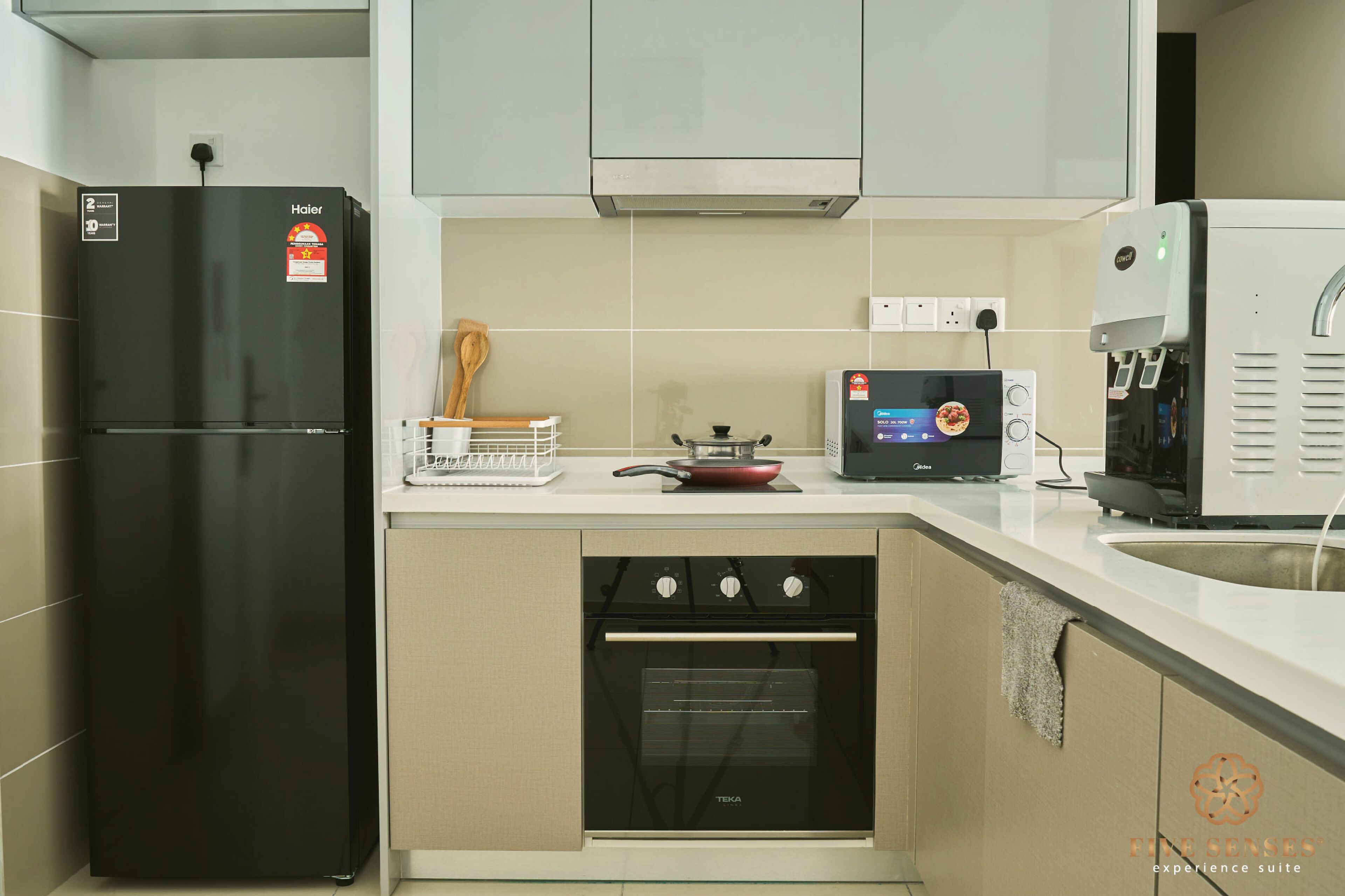 A modern kitchen with a black refrigerator, a built-in oven, a coffee machine, and a small stove.
