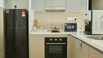 A modern kitchen with a black refrigerator, a built-in oven, a coffee machine, and a small stove.