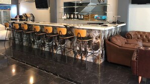 A modern kitchen with a marble island, bar stools, and a brown leather sofa. - The Freelancer Hotel (Pattaya)