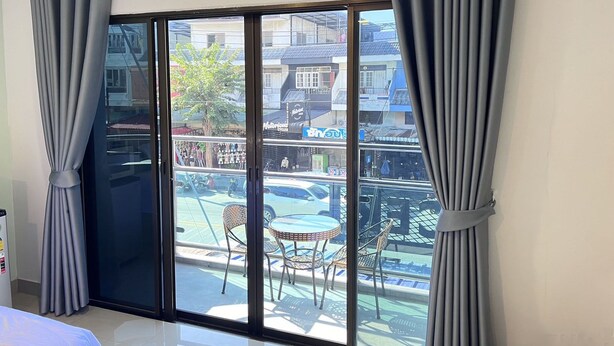A room with a sliding glass door leading to an outdoor area with a table and chairs. - The Freelancer Hotel (Pattaya)