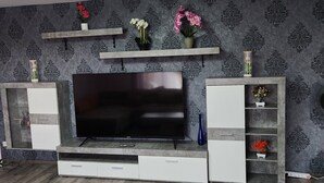 Un soggiorno moderno con televisore a schermo piatto, scaffali a incasso e vasi decorativi.