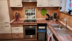 Una cucina moderna con mobili in legno, un piano cottura in acciaio inox, una lavastoviglie e una macchina per il caffè.